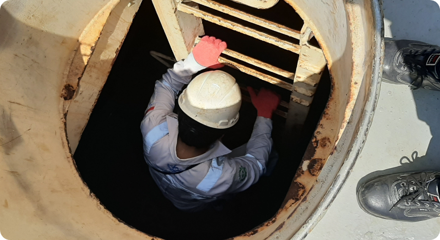 作業員がタンク内部に入り、洗浄後の残渣物の回収作業を行っている様子